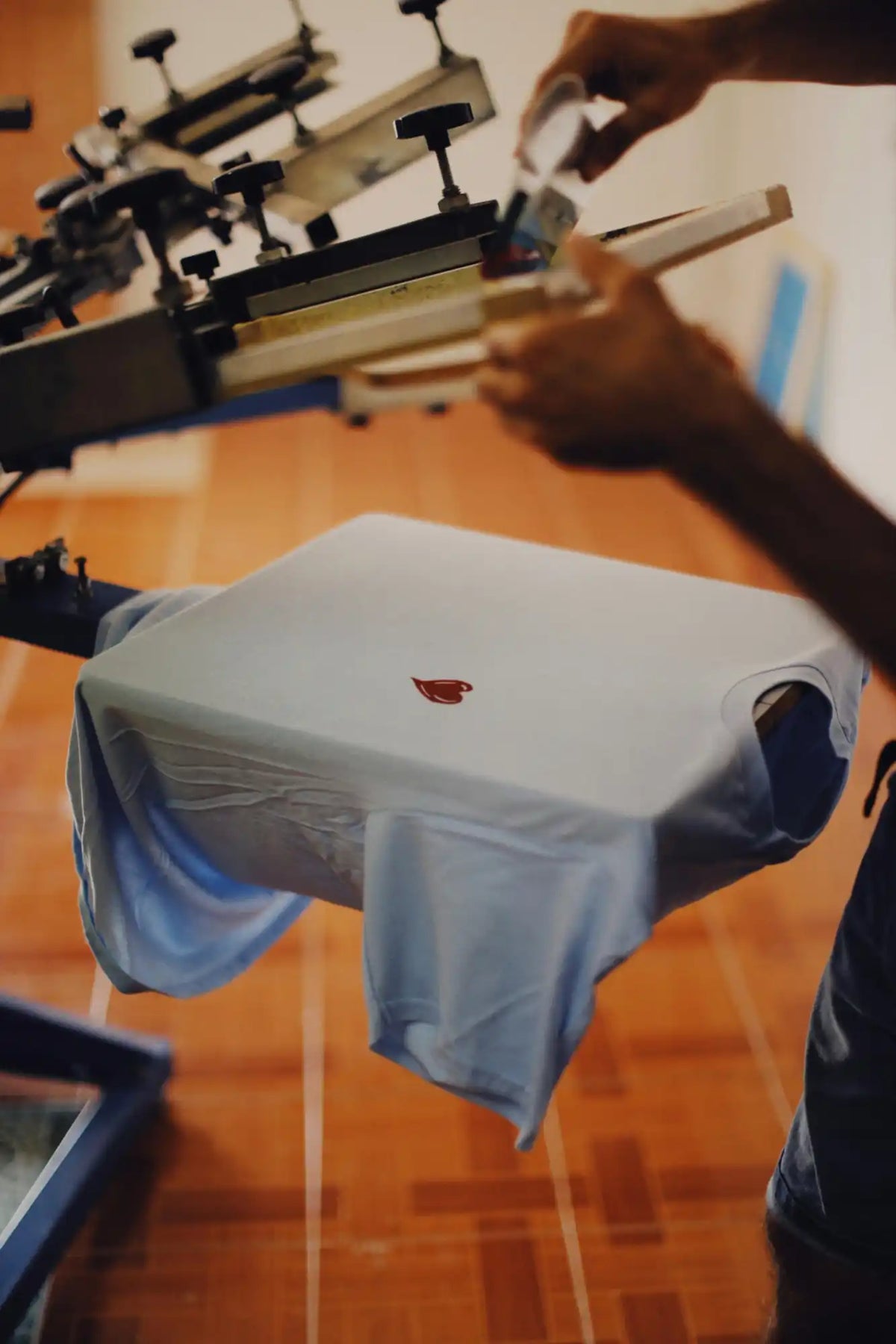 Light blue T-shirt with small red design showcasing printing prices for screen printing and transfer printing