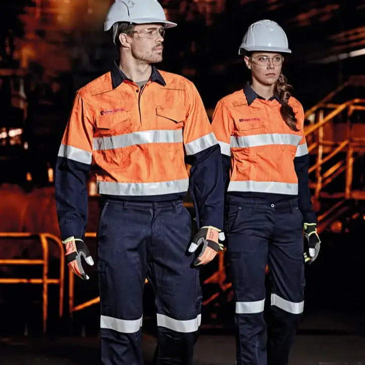 Two individuals wearing high visibility safety uniforms with reflective stripes in Australia on construction worksite for protective workwear